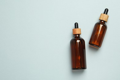 Photo of Bottles of face serum on light grey background, flat lay. Space for text