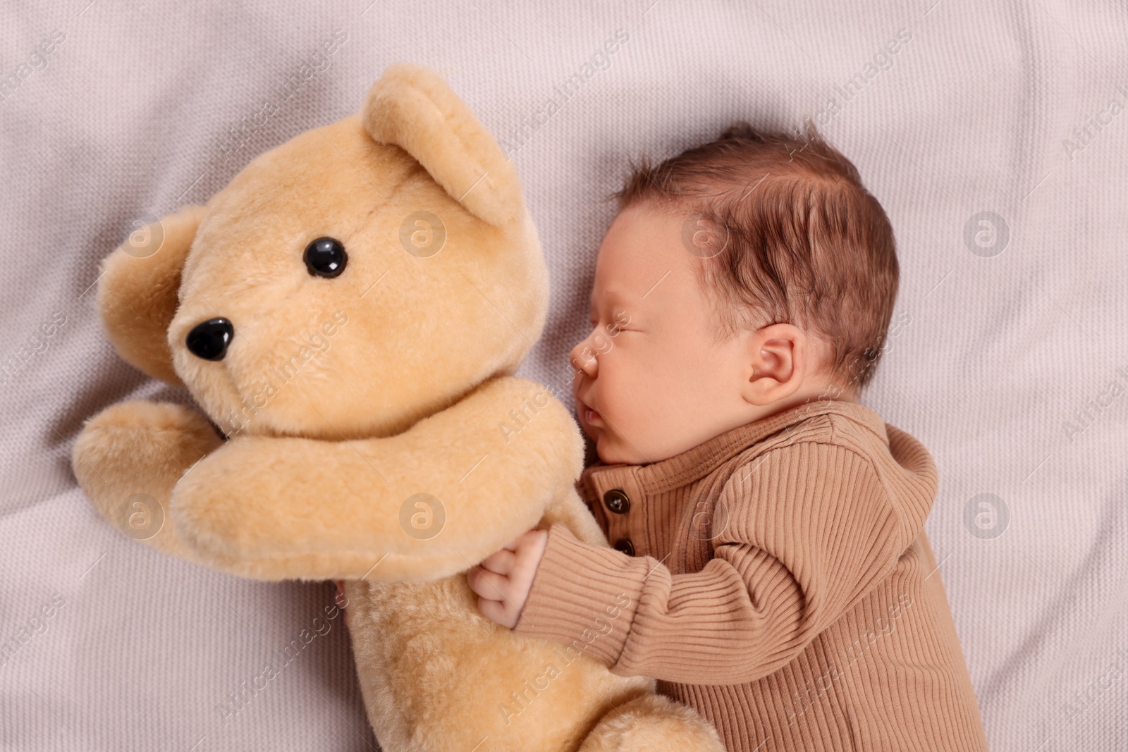 Photo of Cute newborn baby sleeping with toy bear on blanket, top view