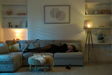 Woman resting on couch in room at night