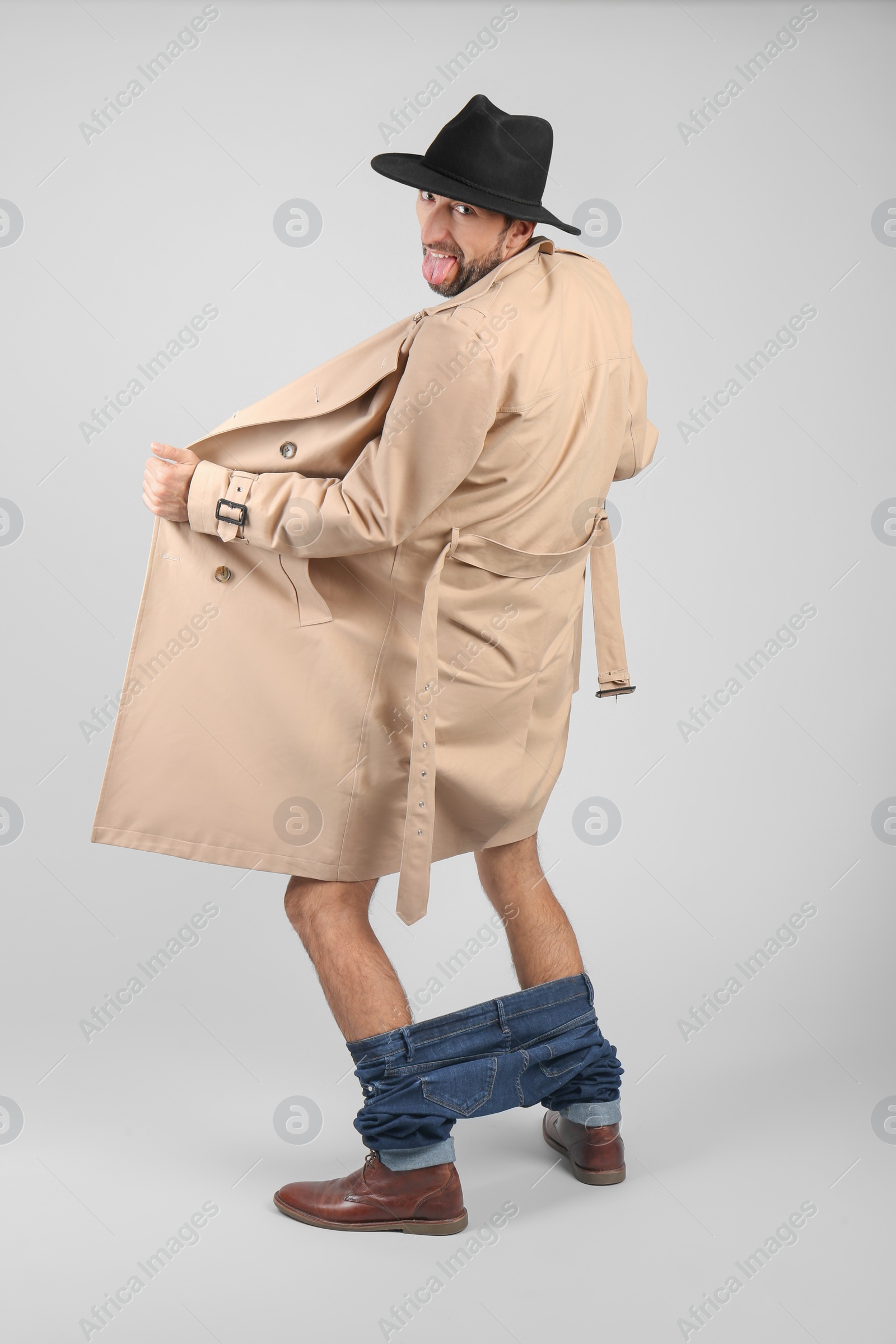 Photo of Exhibitionist exposing naked body under coat on light background