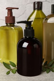 Photo of Shampoo bottles and leaves on light grey table