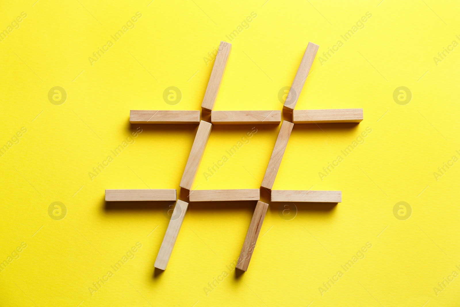 Photo of Hashtag symbol made of wooden blocks on yellow background, top view