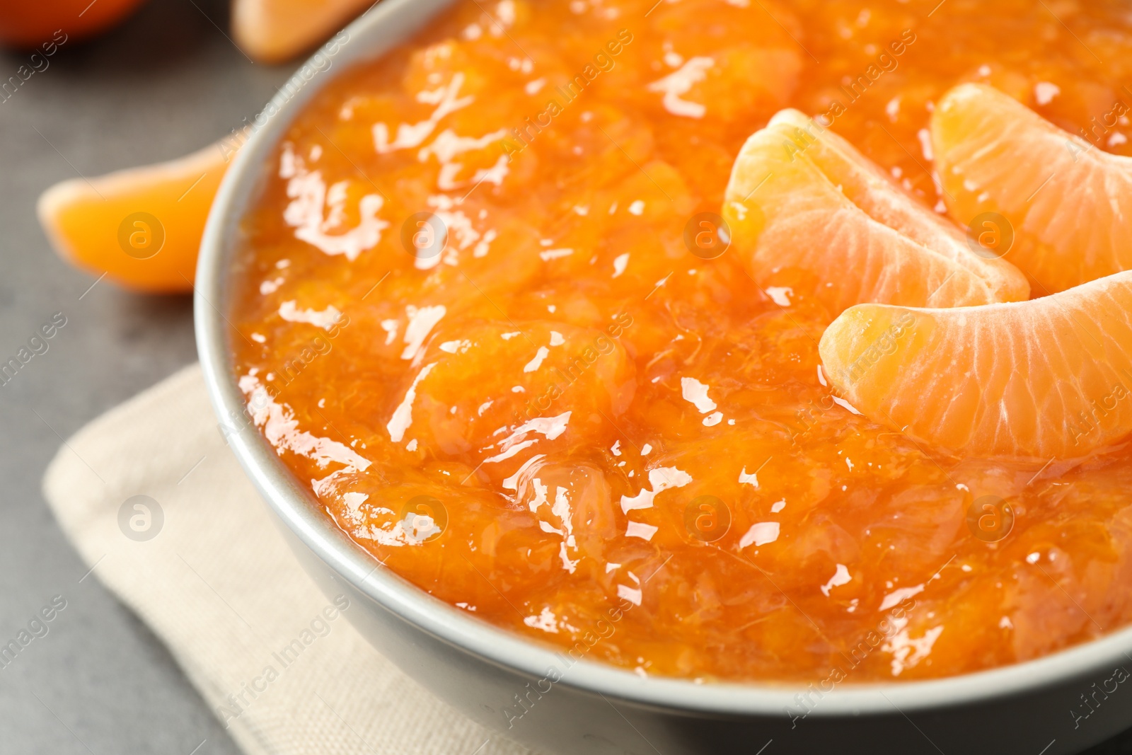 Photo of Tasty tangerine jam in bowl on table, closeup