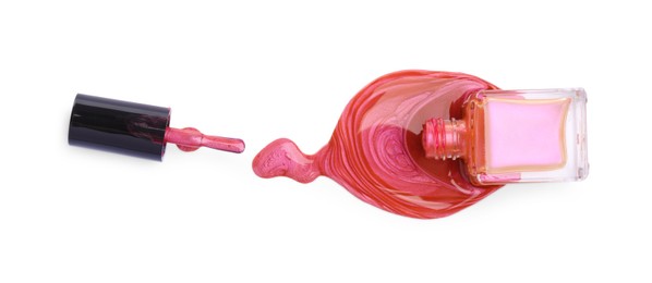 Photo of Overturned bottle of bright nail polish and brush isolated on white, top view