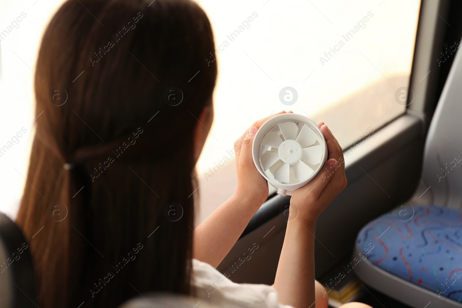 Photo of Woman with portable fan in bus. Summer heat