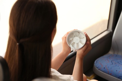 Photo of Woman with portable fan in bus. Summer heat