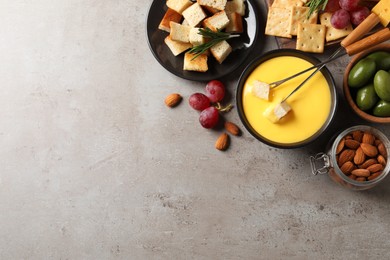 Photo of Tasty cheese fondue and snacks on grey table, flat lay. Space for text