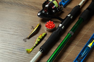 Photo of Spinning rods and fishing tackle on wooden background, closeup. Space for text