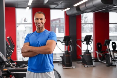Photo of Happy trainer in modern gym, space for text