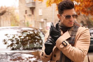 Photo of Handsome stylish man putting on black leather gloves outdoors. Space for text