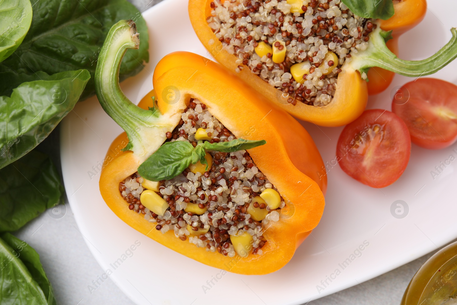 Photo of Quinoa stuffed bell pepper with basil and tomato on light table, top view