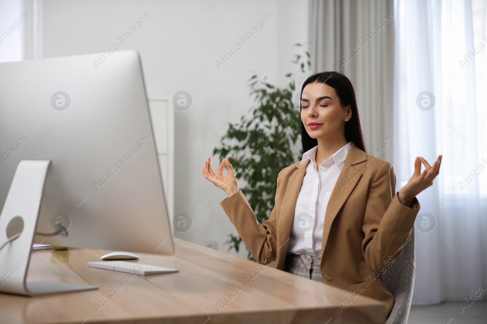 Photo of Young woman meditating at workplace. Stress relief exercise