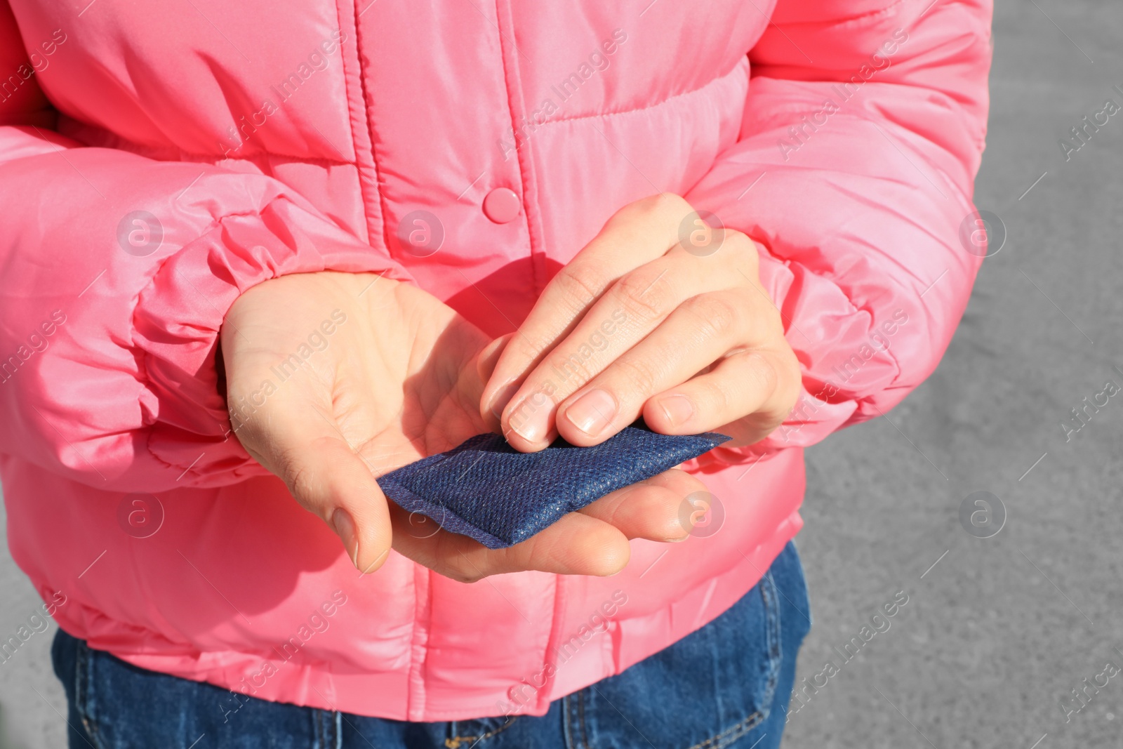 Photo of Woman holding hand warmer outdoors, closeup view