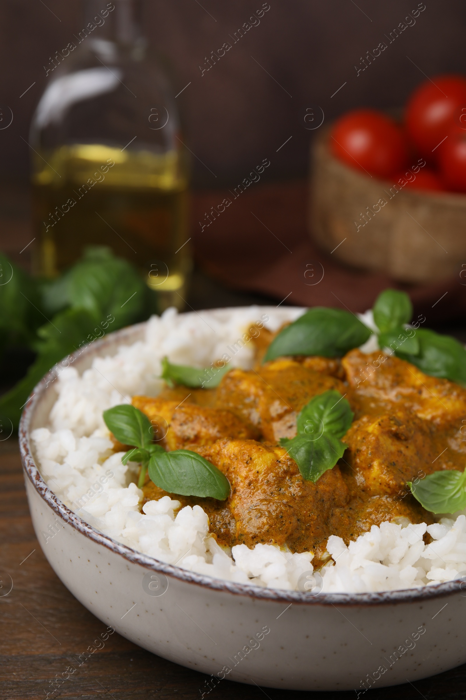 Photo of Delicious rice and chicken with curry sauce served on wooden table, closeup