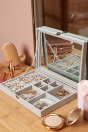 Photo of Elegant jewelry box with beautiful bijouterie and makeup products on wooden table