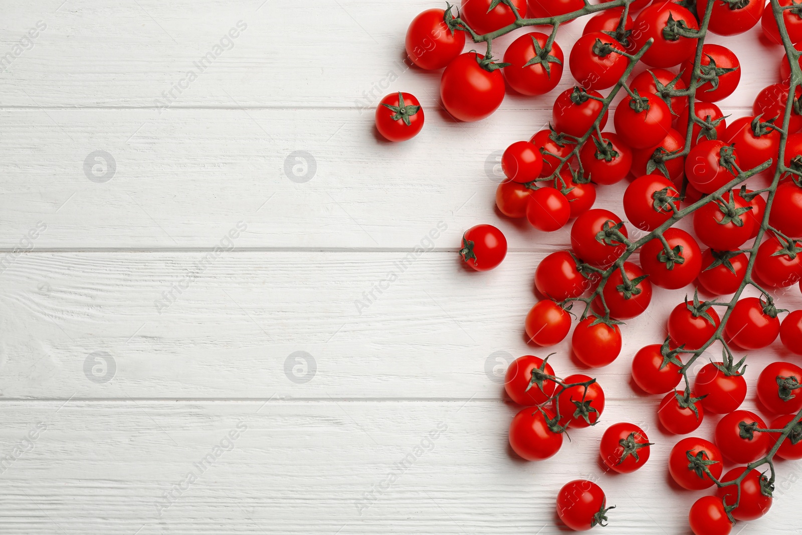 Photo of Fresh ripe cherry tomatoes on white wooden table, flat lay. Space for text