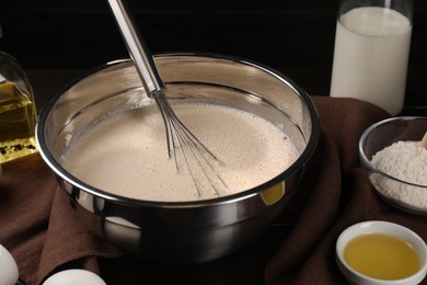 Photo of Dough and whisk in bowl on table, closeup