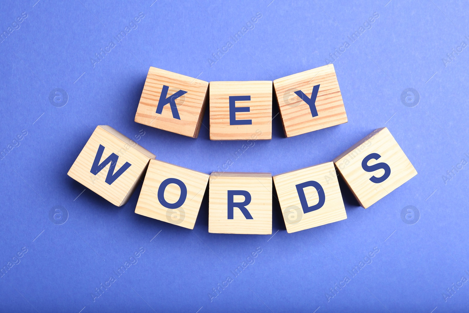 Photo of Wooden cubes with word KEYWORDS on blue background, flat lay