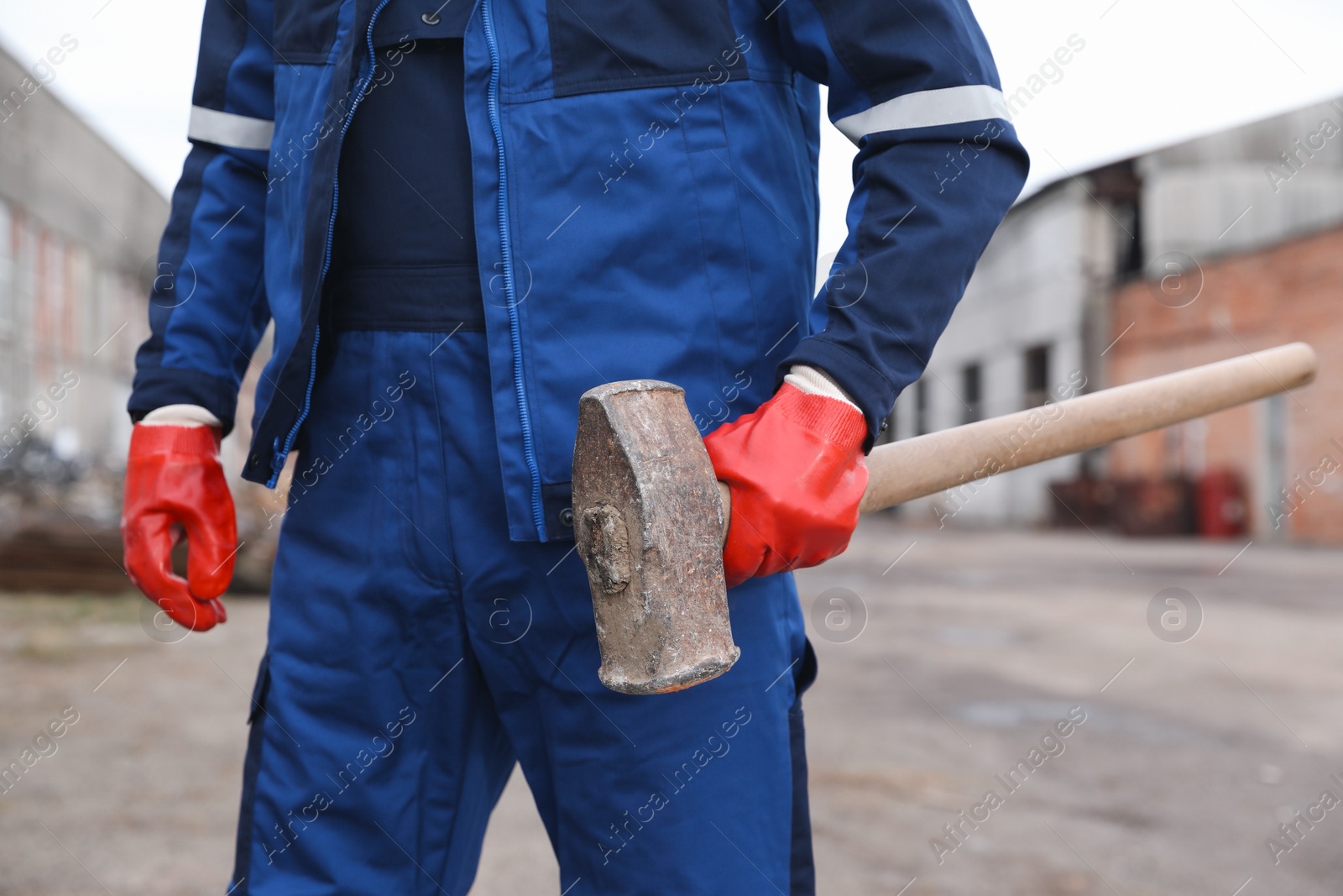 Photo of Man in uniform with sledgehammer outdoors, closeup