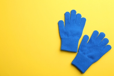 Pair of stylish woolen gloves on yellow background, flat lay. Space for text
