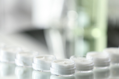 Photo of Small jars with cream in cosmetic laboratory