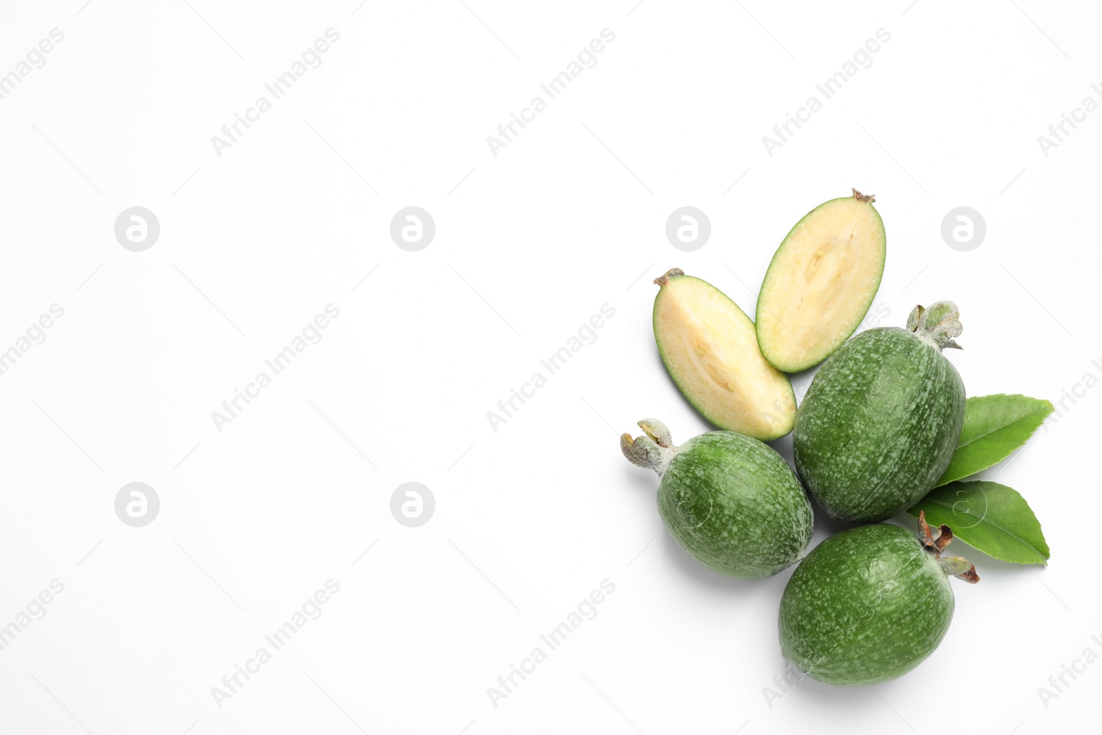 Photo of Cut and whole feijoas with leaves on white background, top view