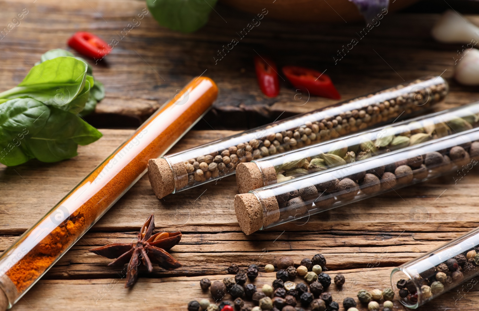 Photo of Fragrant spices in glass test tubes on wooden table, closeup