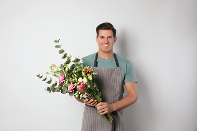 Photo of Florist with beautiful bouquet on light background