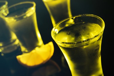 Shot glasses of vodka with lemon slice on dark background, closeup. Space for text