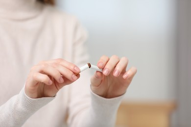 Stop smoking concept. Woman breaking cigarette on blurred background, closeup. Space for text