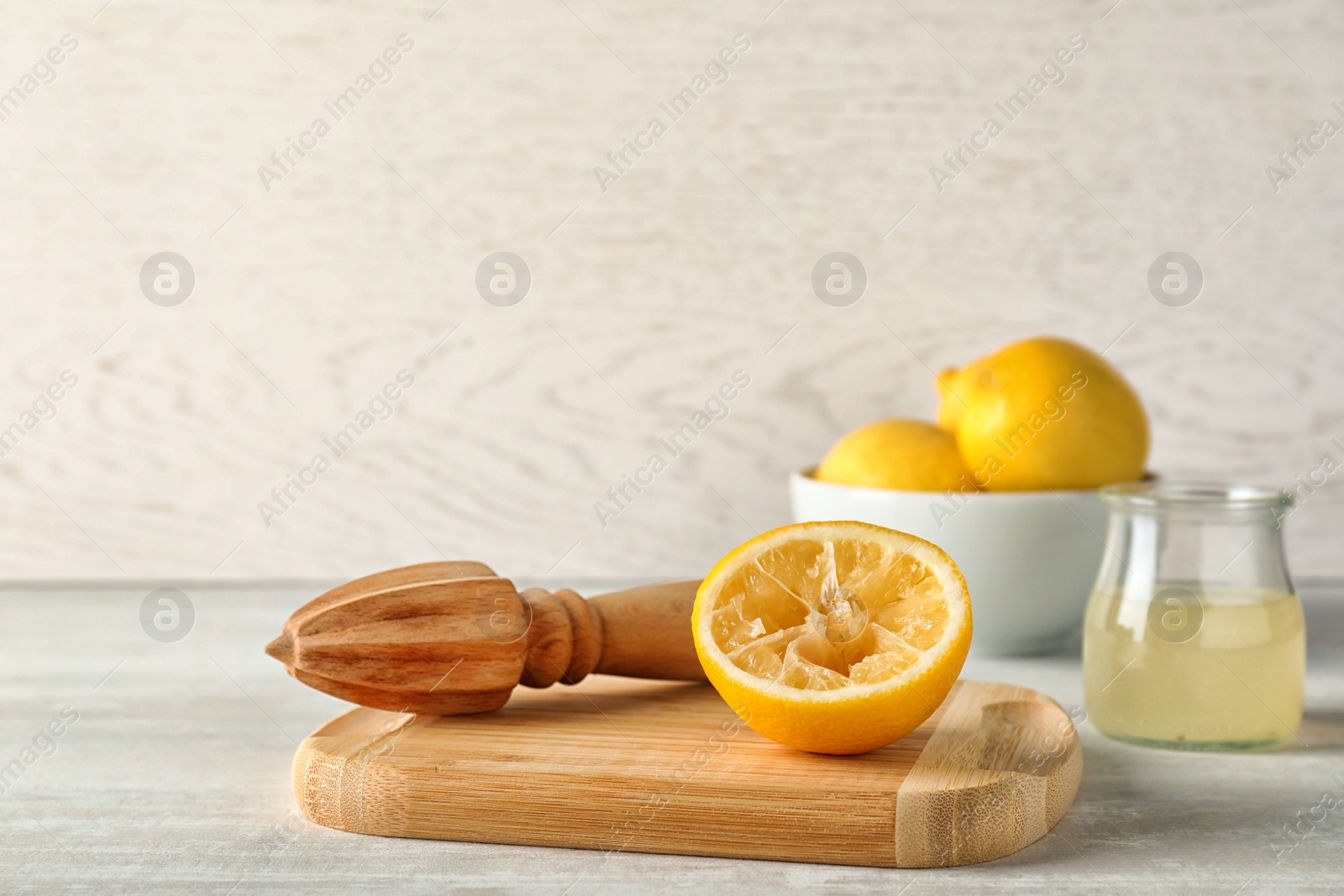 Photo of Wooden board with lemon reamer and squeezed fruit on table