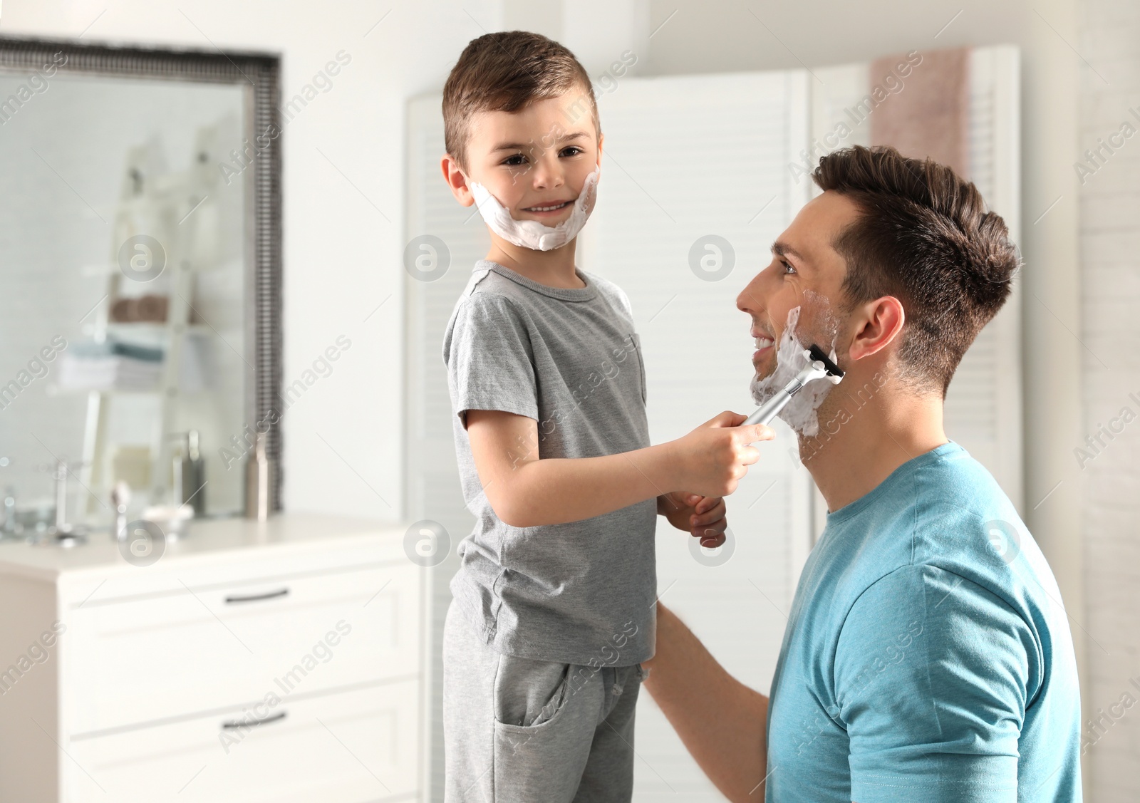 Photo of Little son shaving his dad in bathroom