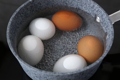 Chicken eggs boiling in saucepan on electric stove, closeup