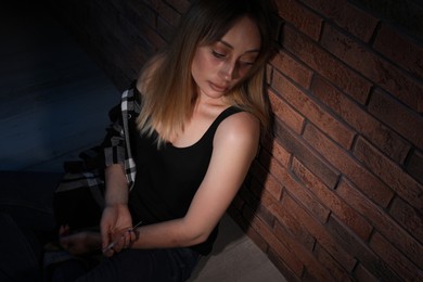 Overdosed drug addicted woman near brick wall