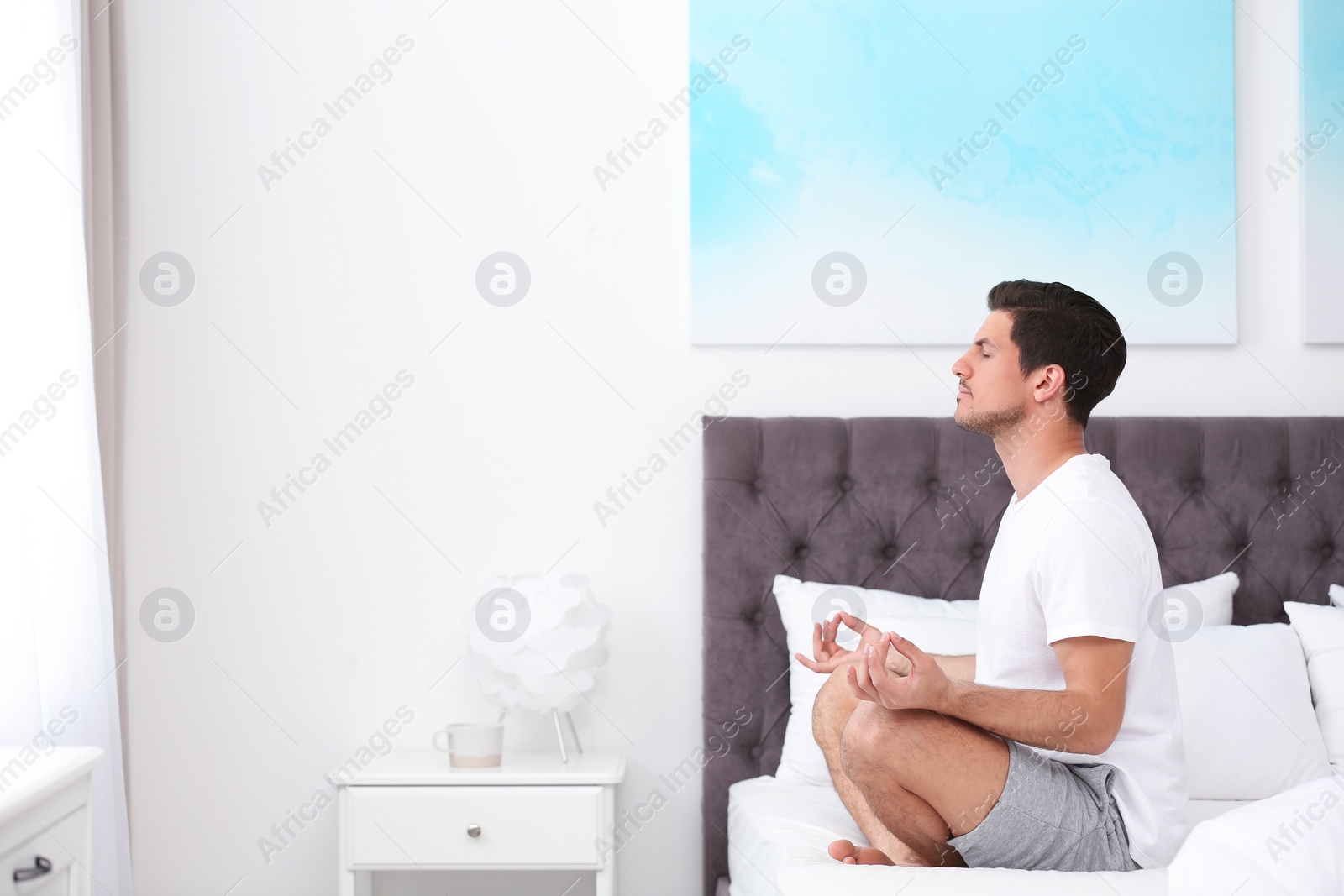 Photo of Man meditating on bed at home, space for text. Zen concept