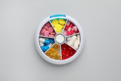 Photo of Plastic box with different pills on light grey background, top view