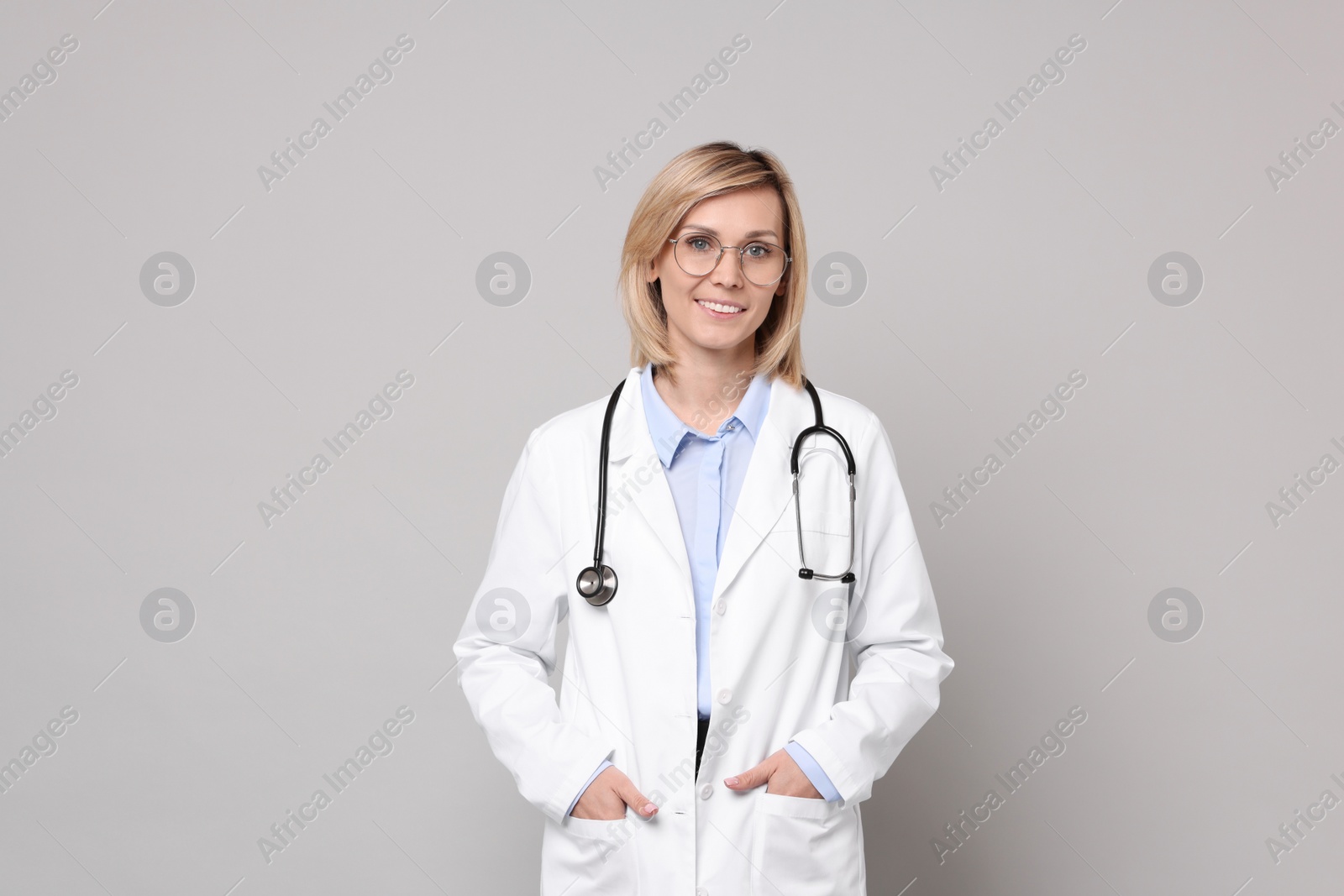 Photo of Portrait of smiling doctor on grey background