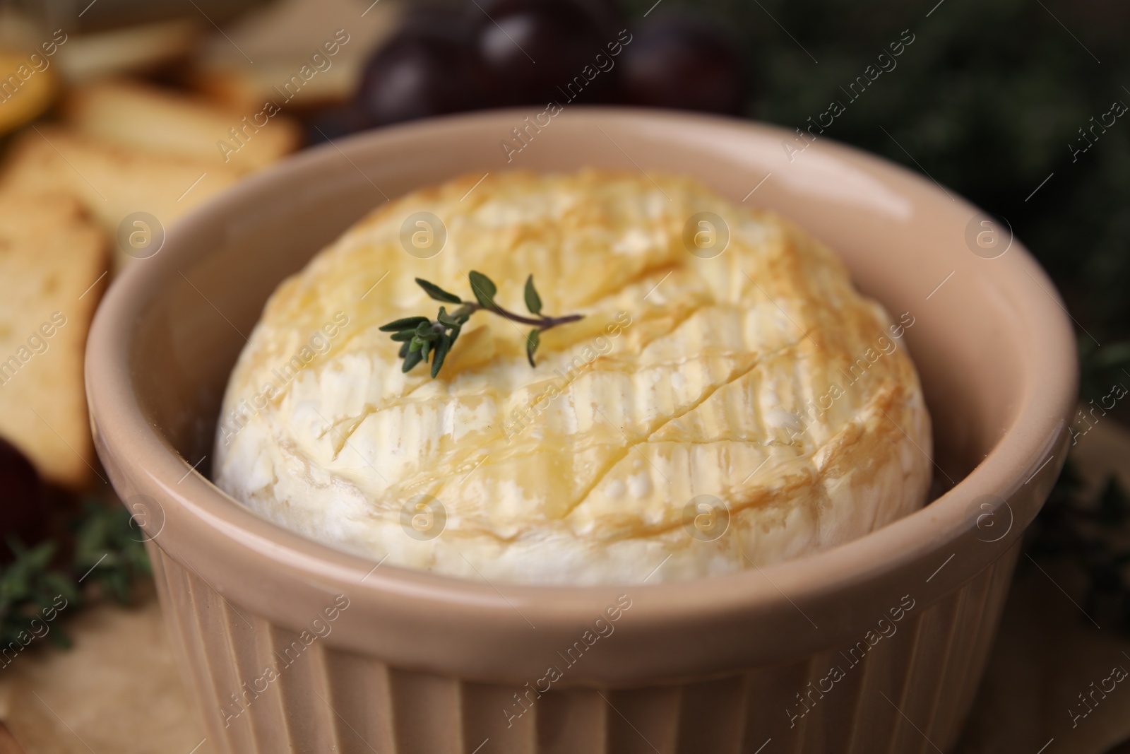 Photo of Tasty baked camembert in bowl on table, closeup