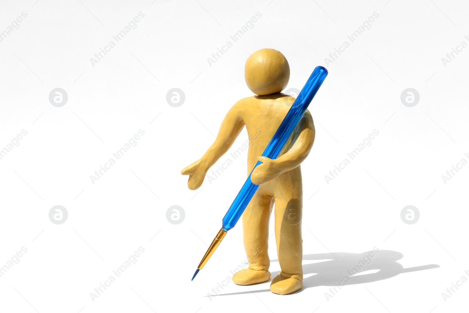 Photo of Human figure made of yellow plasticine holding paintbrush on white background. Space for text