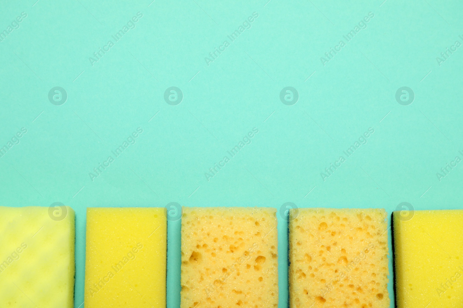 Photo of Many sponges on turquoise background, flat lay. Space for text
