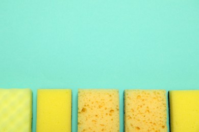 Photo of Many sponges on turquoise background, flat lay. Space for text