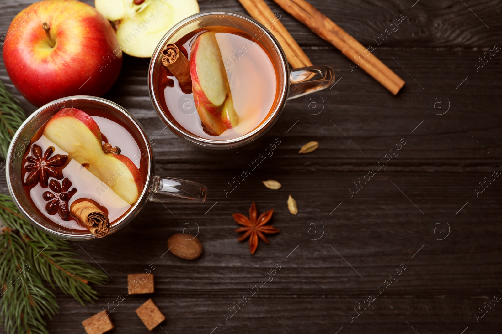 Photo of Aromatic hot mulled cider on black wooden table, flat lay. Space for text