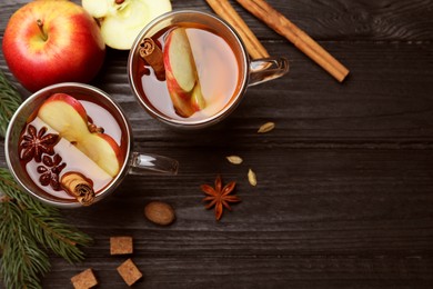 Photo of Aromatic hot mulled cider on black wooden table, flat lay. Space for text