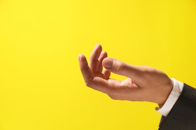 Man holding something in hand on yellow background, closeup. Space for text