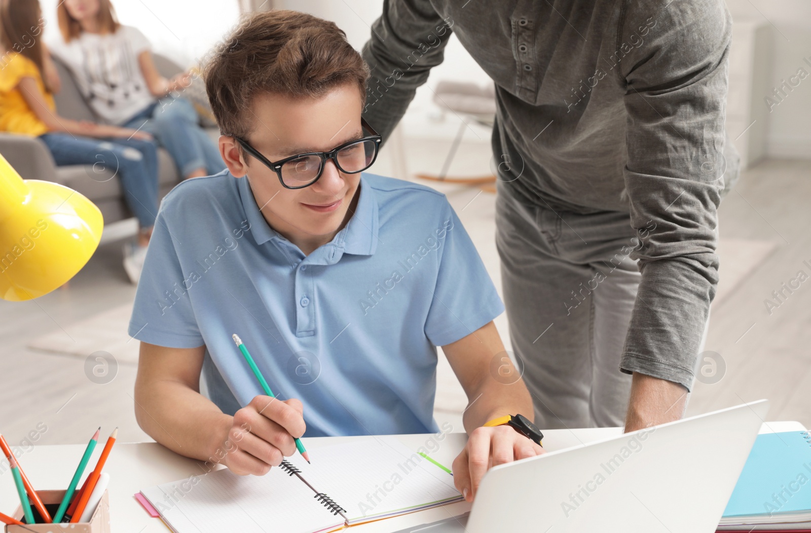 Photo of Father helping his teenager son with homework indoors