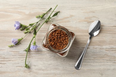 Photo of Jar of chicory granules, spoon and flowers on white wooden table, flat lay