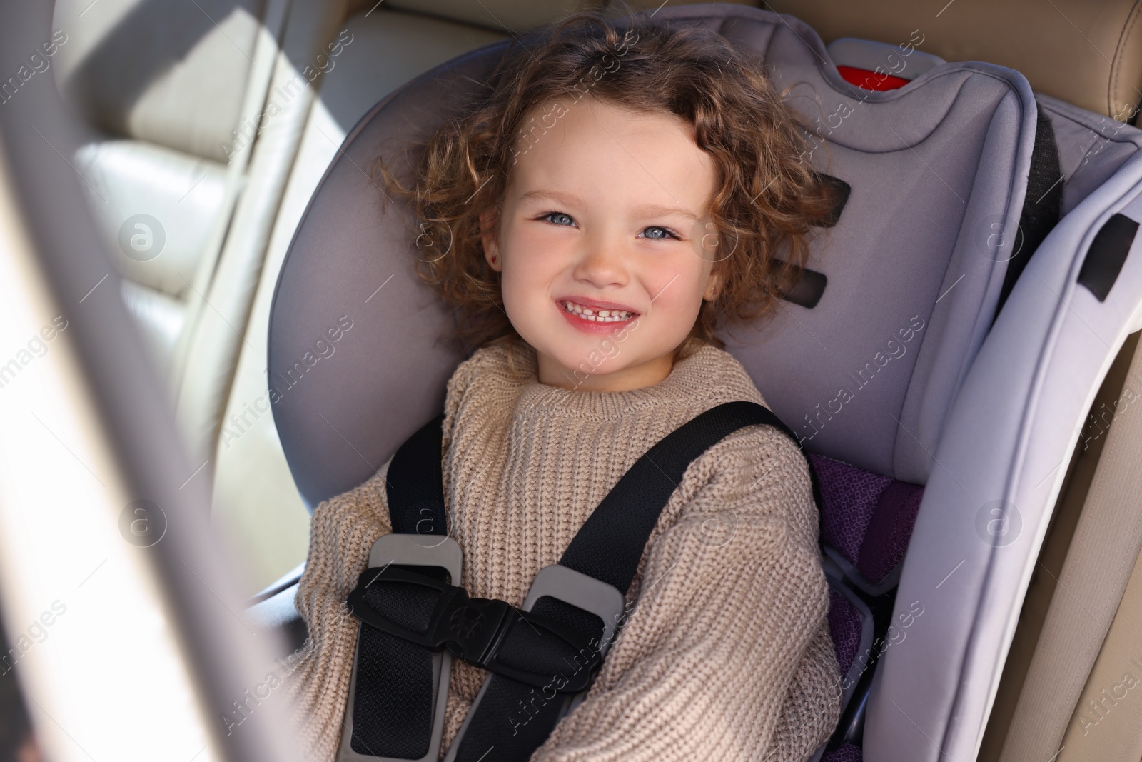 Photo of Cute little girl sitting in child safety seat inside car