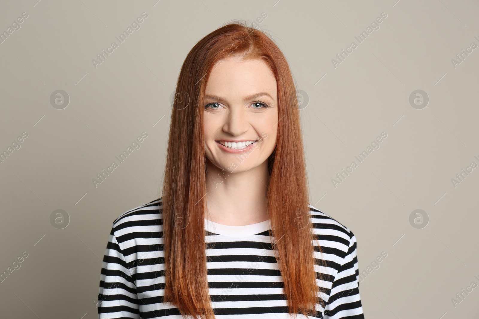 Photo of Candid portrait of happy young woman with charming smile and gorgeous red hair on beige background