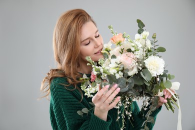 Beautiful woman with bouquet of flowers on grey background