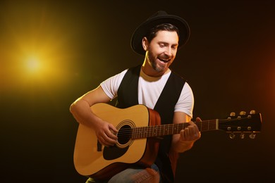 Photo of Handsome man with acoustic guitar singing while woman holding microphone on dark background, closeup